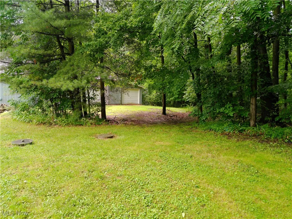 View of green lawn featuring a detached garage