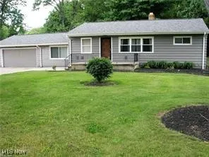 Ranch-style home with an attached garage, a front yard, a chimney, and concrete driveway