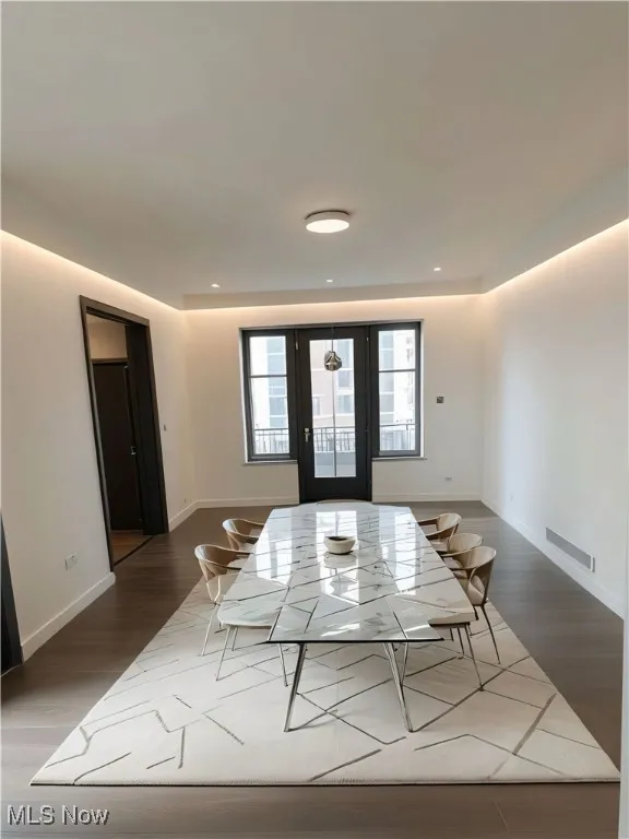 This picture is AI STAGED for imaginary purposes. Dining room are featuring wood finished floors and french doors