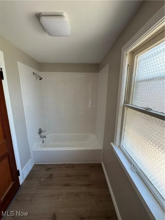 Full bath with tub / shower combination and wood finished floors