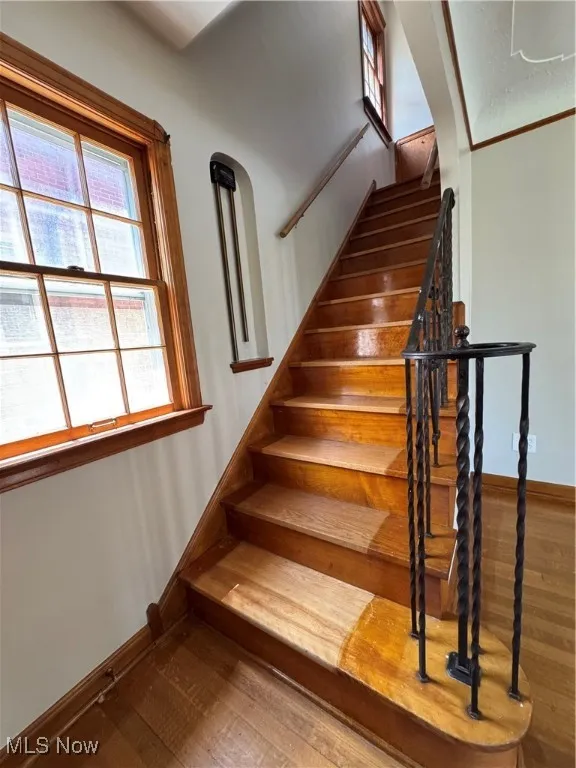 Staircase with hardwood / wood-style flooring and baseboards