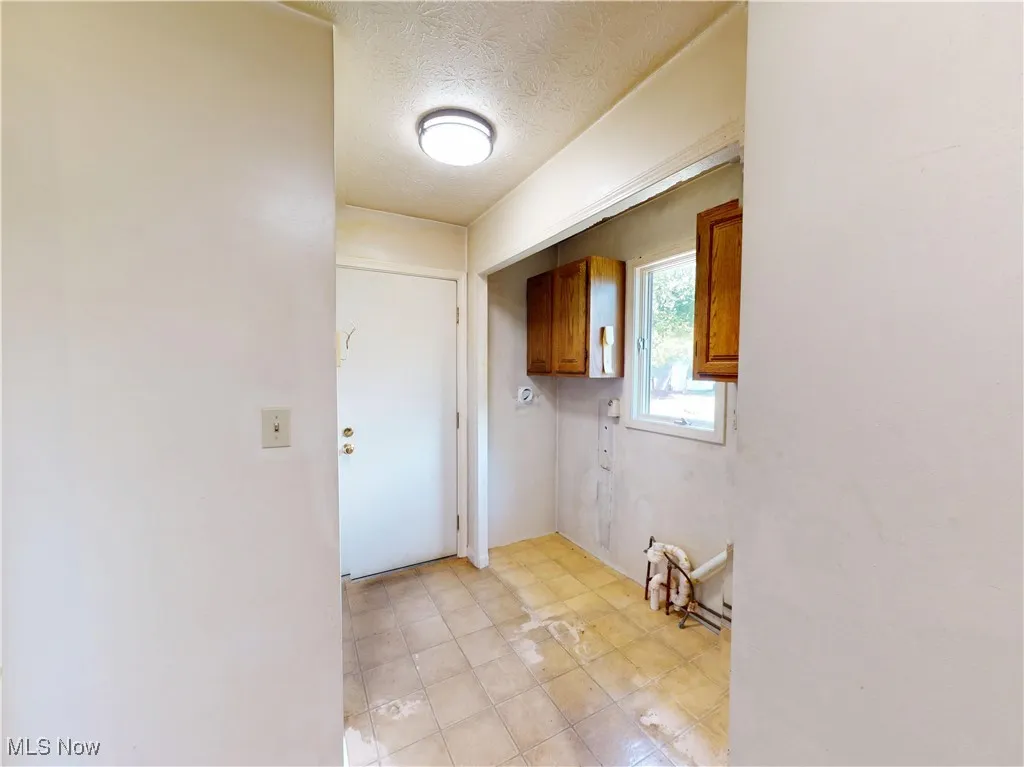 Laundry room featuring cabinet space and a textured ceiling