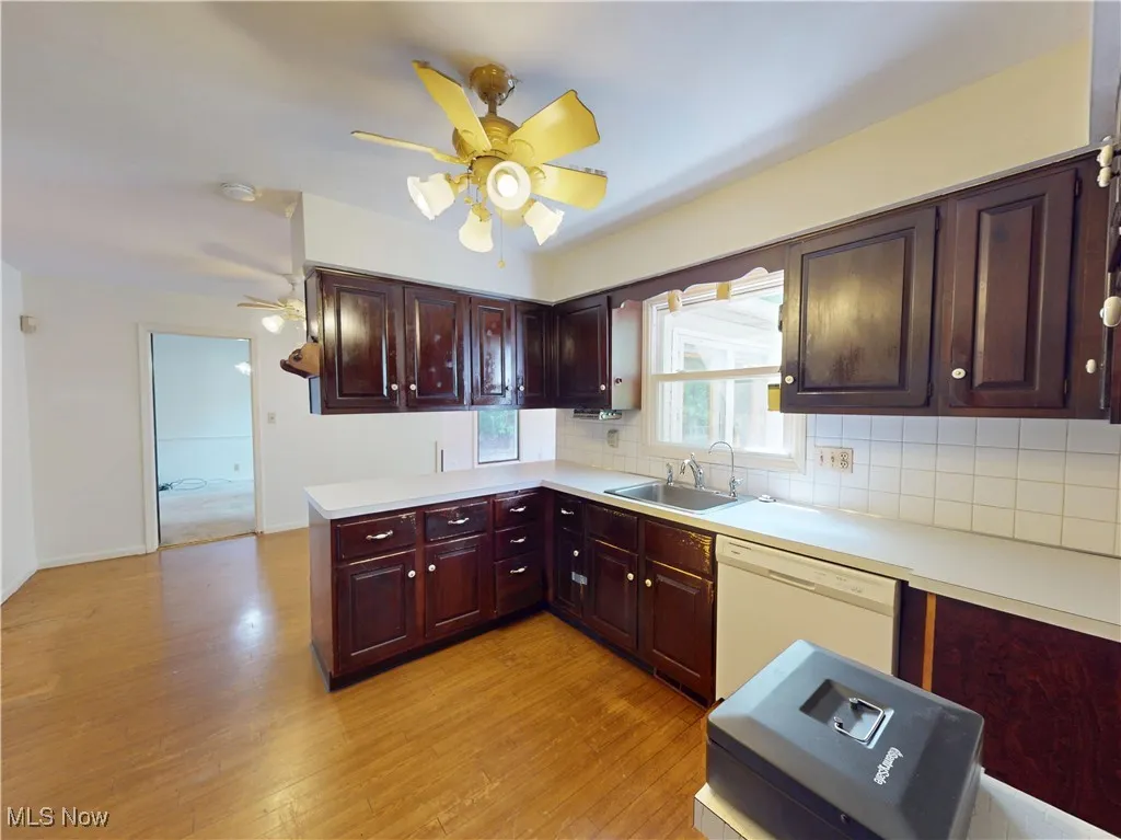 Kitchen featuring white dishwasher, a ceiling fan, light countertops, and light wood finished floors