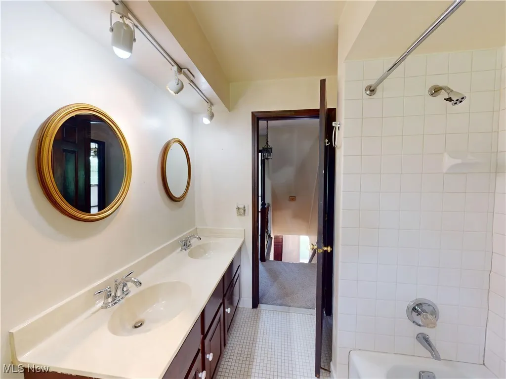 Full bath featuring double vanity, bathing tub / shower combination, and tile patterned flooring