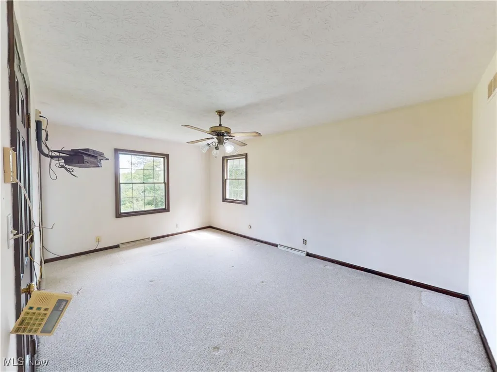 Carpeted spare room with ceiling fan and a textured ceiling