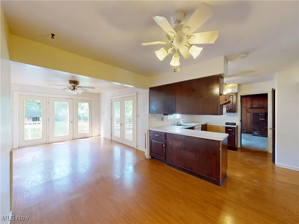 Kitchen with a peninsula, ceiling fan, backsplash, wood finished floors, and french doors