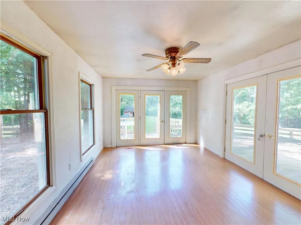 Unfurnished sunroom with french doors and a baseboard heating unit