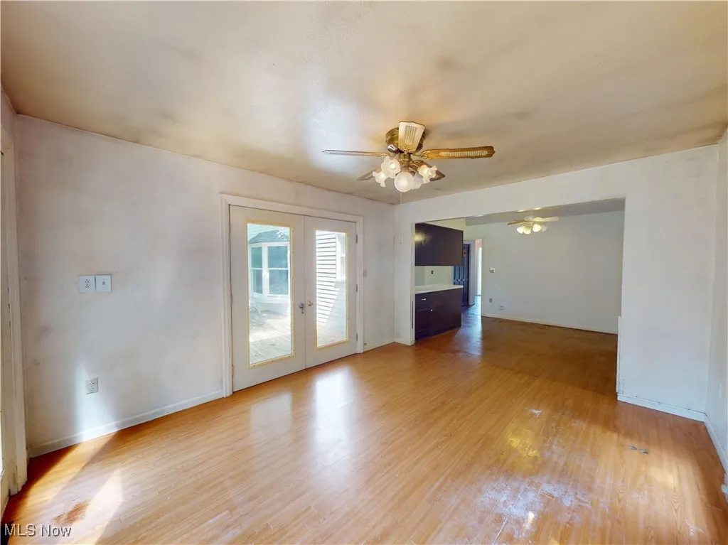 Unfurnished living room featuring french doors, a ceiling fan, and light wood-style floors