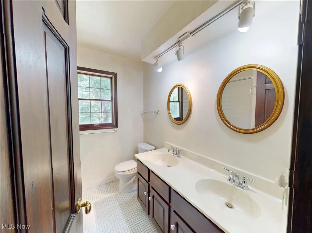 Full bath with track lighting, double vanity, and tile patterned floors