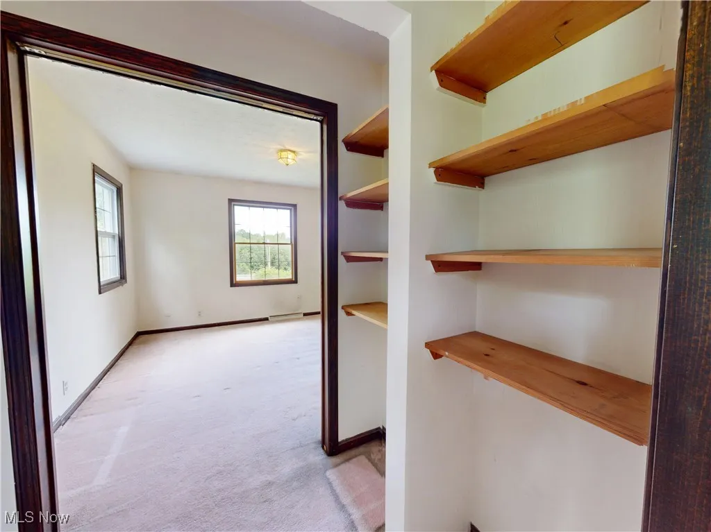 Hallway with light colored carpet and baseboards