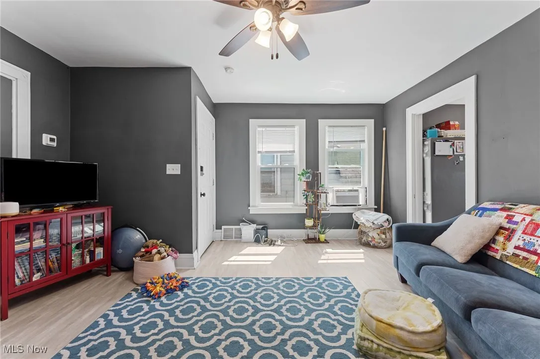 Living area with wood finished floors, a ceiling fan, and cooling unit