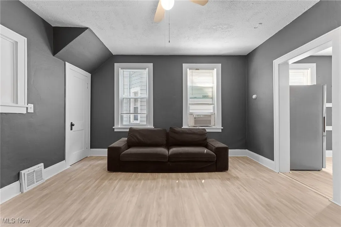 Living area featuring wood finished floors, a textured ceiling, a ceiling fan, and cooling unit
