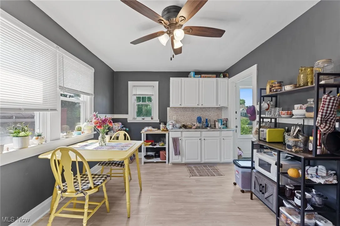 Kitchen with ceiling fan, plenty of natural light, white cabinets, and light wood-style floors