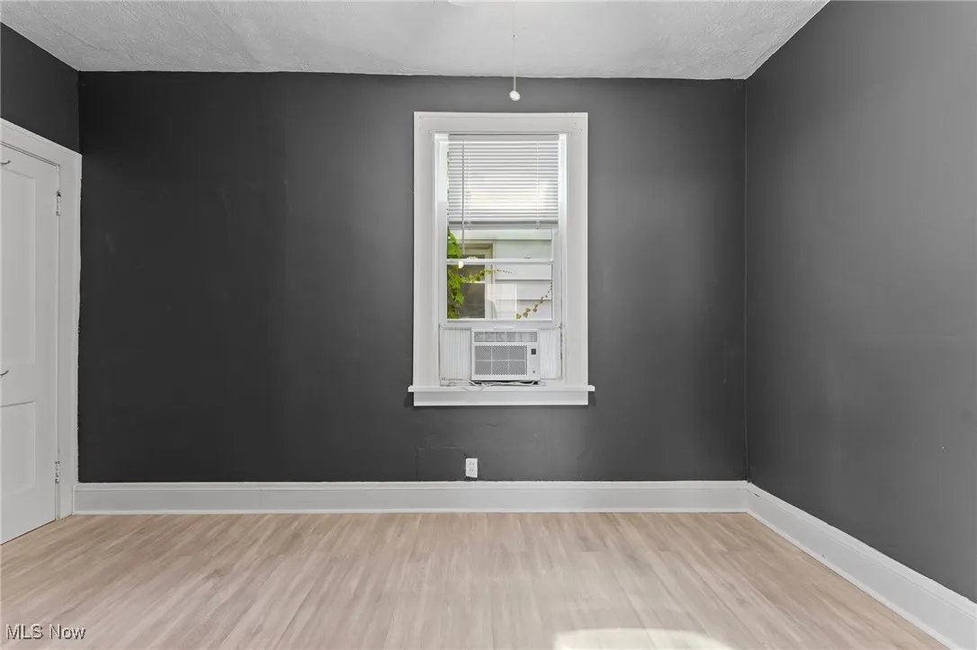 Unfurnished room with wood finished floors, cooling unit, and a textured ceiling