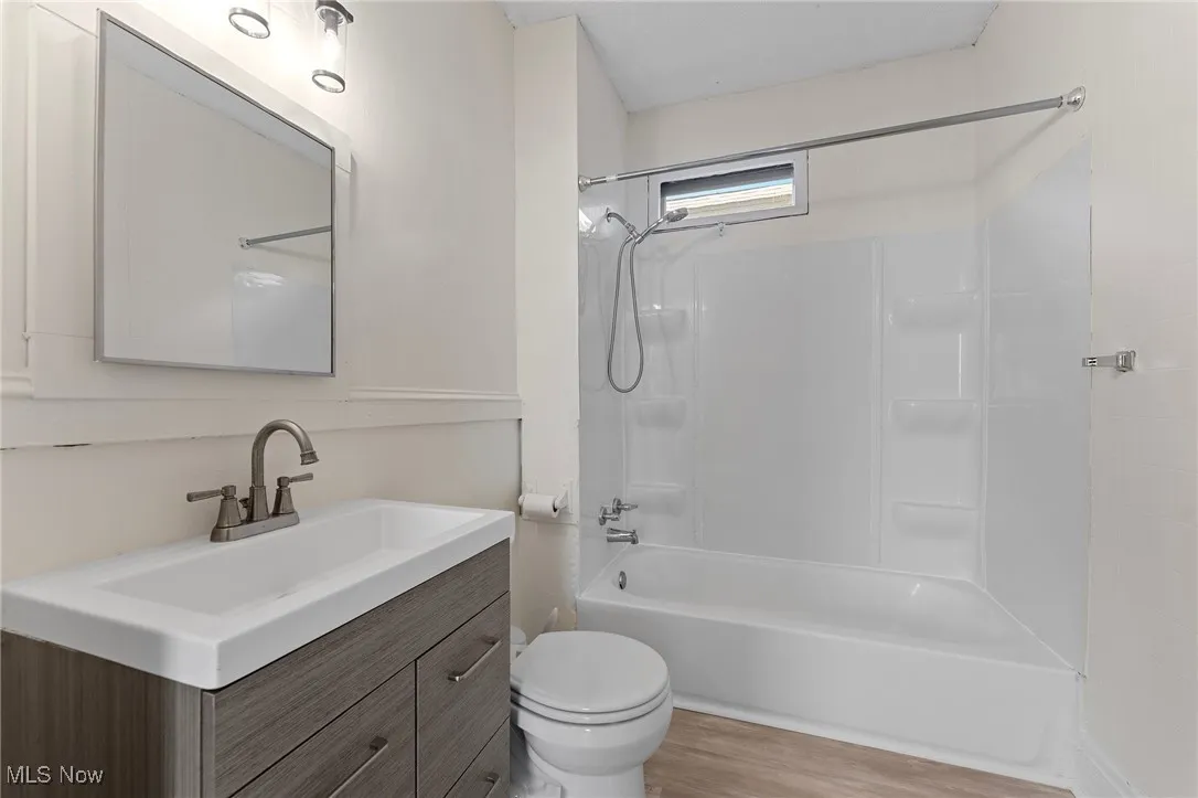 Bathroom featuring vanity, shower / tub combination, and wood finished floors