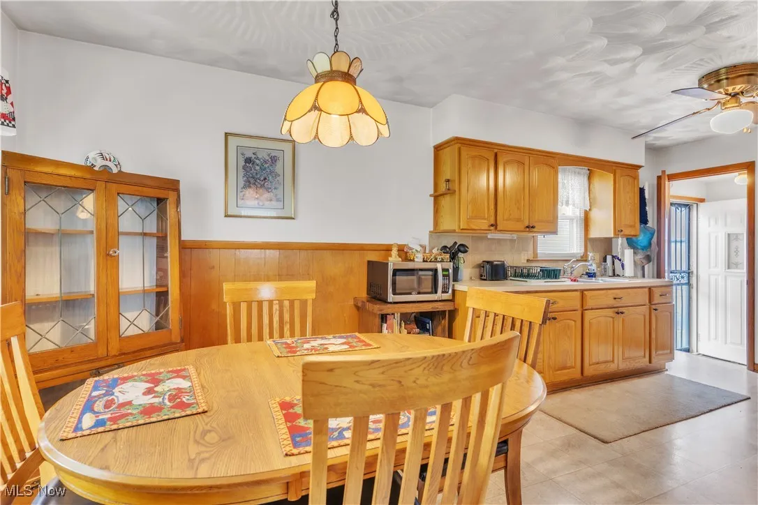 Dining space with wainscoting, a ceiling fan, and wooden walls