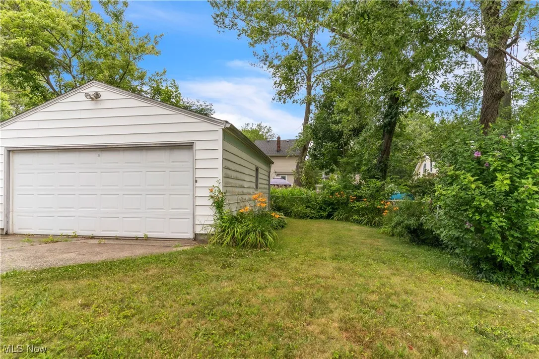 View of green lawn with a garage and an outbuilding