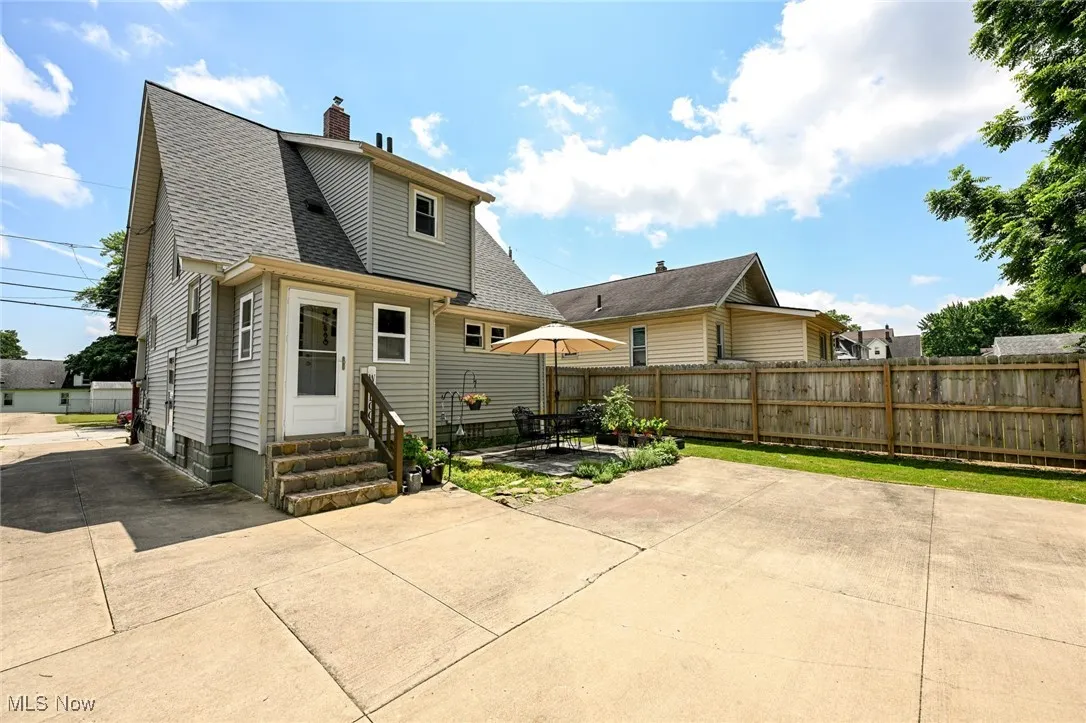 Rear view of house featuring entry steps, a patio, a chimney, and roof with shingles