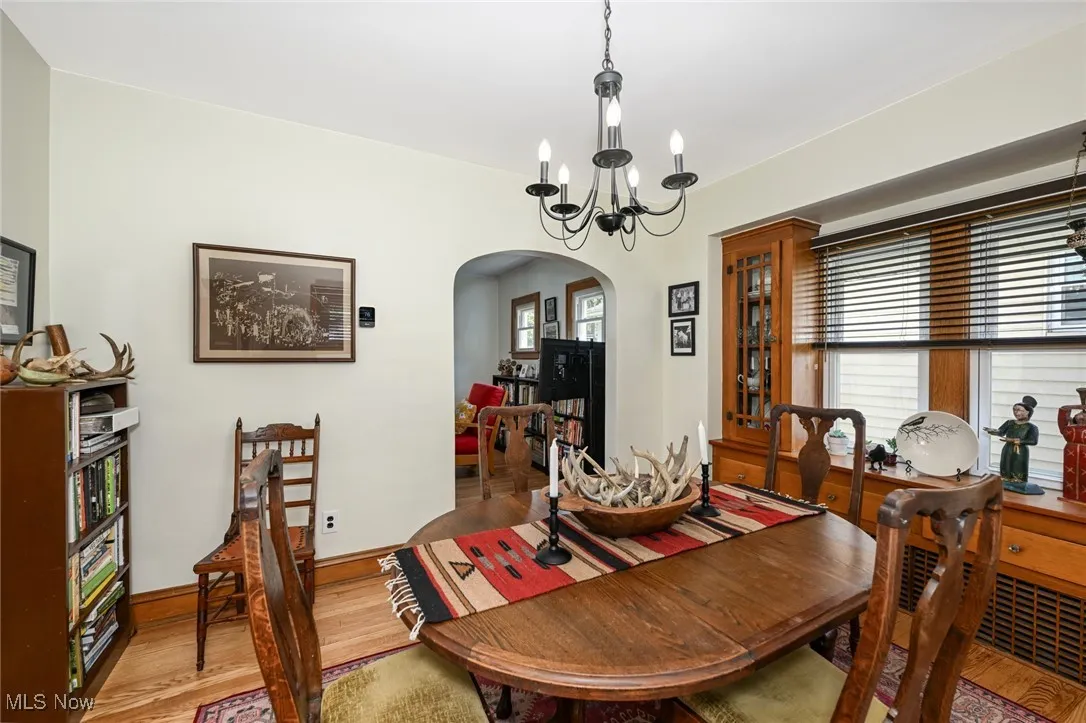 Dining room with arched walkways, light wood finished floors, and a chandelier