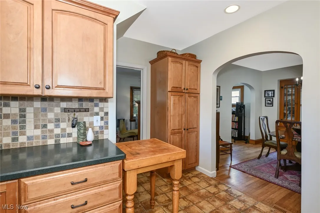 Kitchen featuring arched walkways, backsplash, dark countertops, and recessed lighting