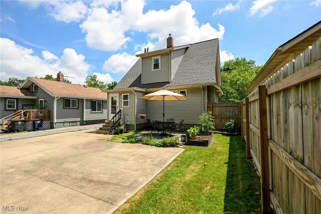 Back of property with a chimney, a fenced backyard, roof with shingles, and a patio