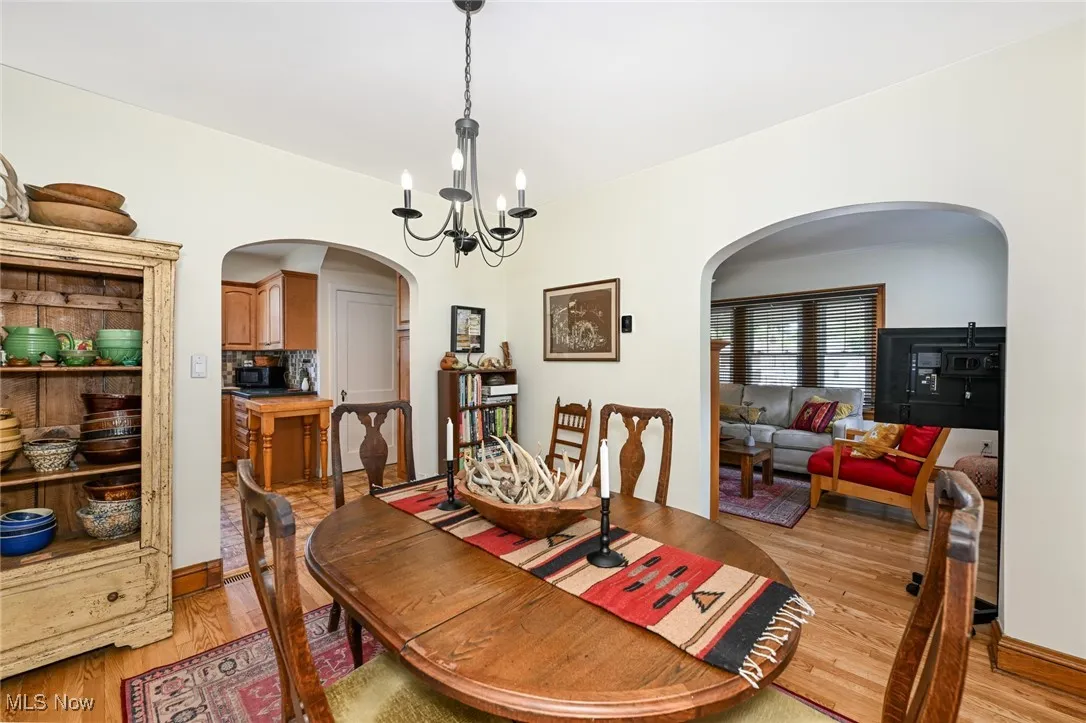 Dining space with arched walkways, a chandelier, and light wood-type flooring