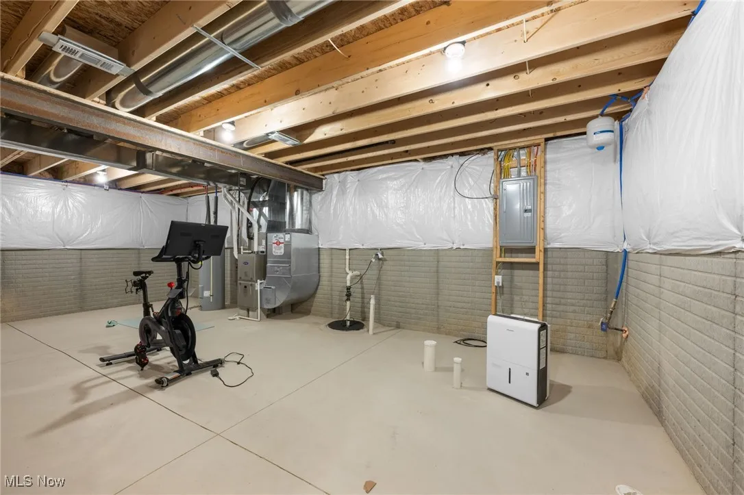 Unfinished below grade area featuring electric panel, brick wall, and heating unit