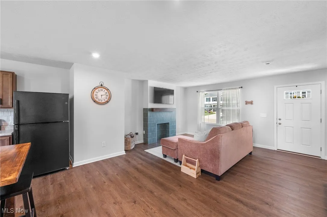 Living area with dark wood-style floors, a tiled fireplace, and recessed lighting