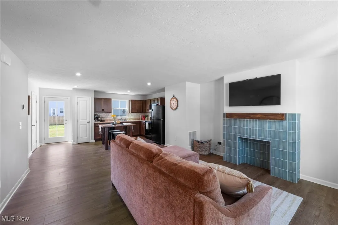 Living area featuring dark wood-style floors, a fireplace, recessed lighting, and a textured ceiling