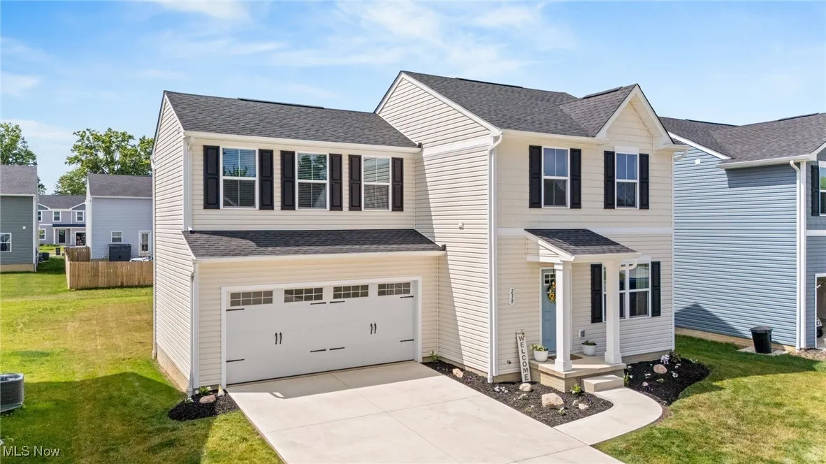 Traditional home featuring driveway, a garage, and a shingled roof