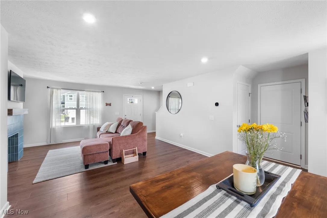 Living room with wood finished floors, recessed lighting, a tiled fireplace, and a textured ceiling