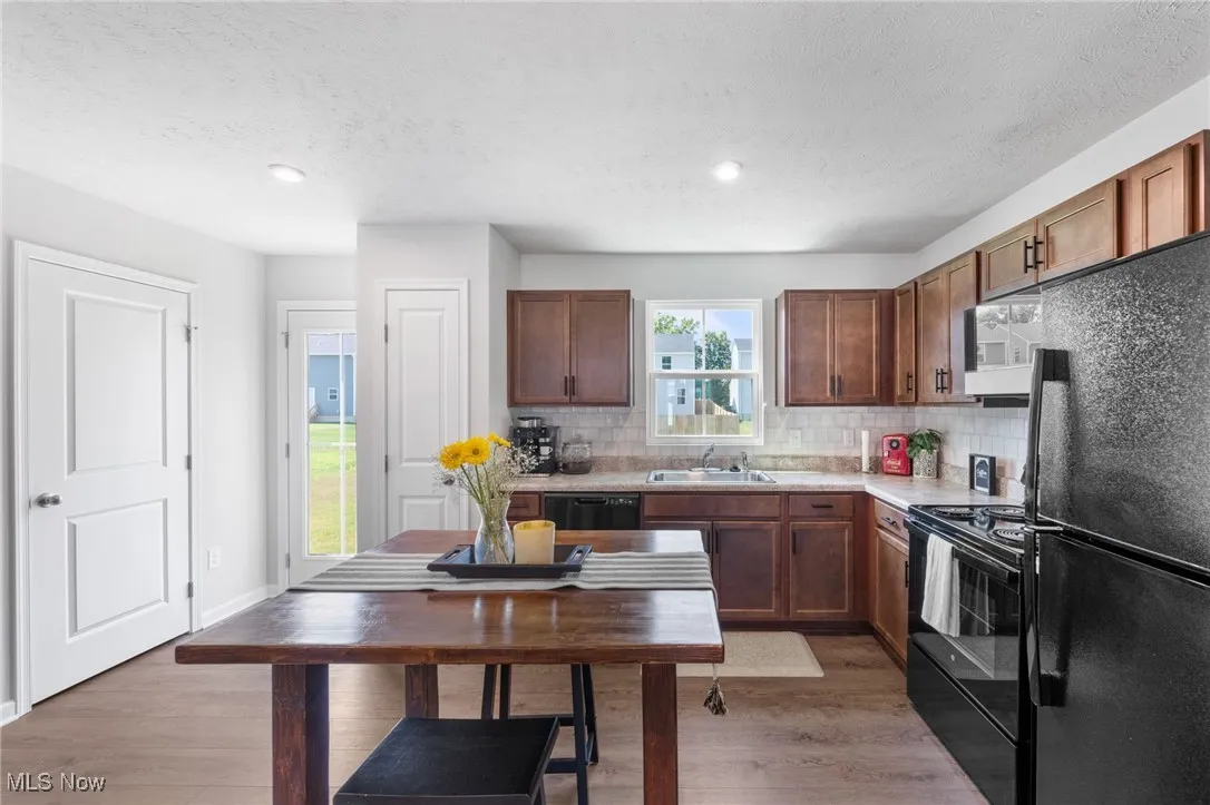 Kitchen with black appliances, light countertops, tasteful backsplash, light wood-style floors, and a textured ceiling