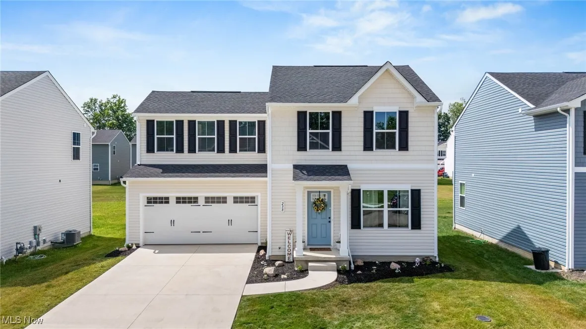 Traditional-style house with concrete driveway, a garage, a front yard, and a shingled roof