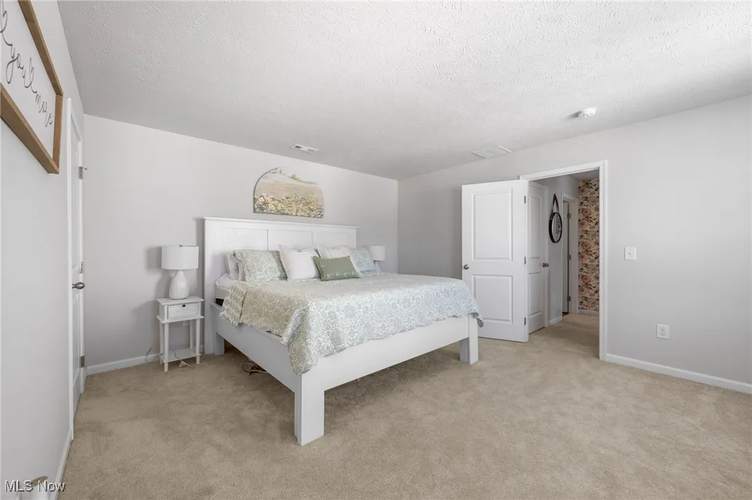 Bedroom with light carpet and a textured ceiling