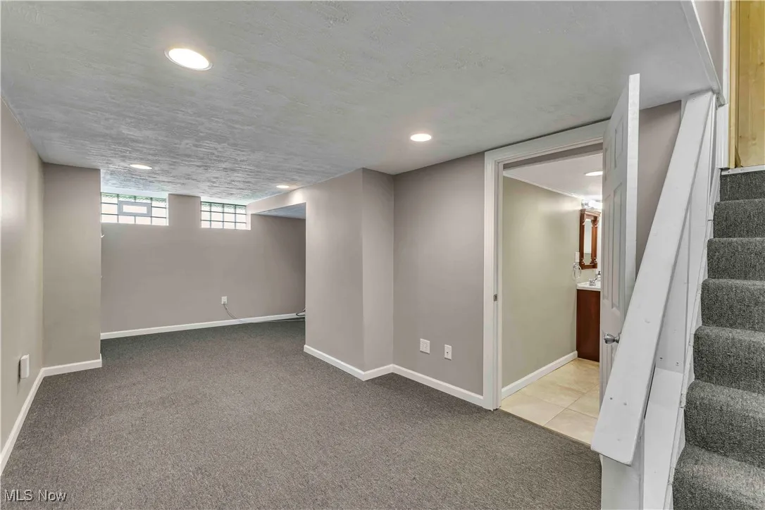 Below grade area with carpet floors, stairs, and recessed lighting