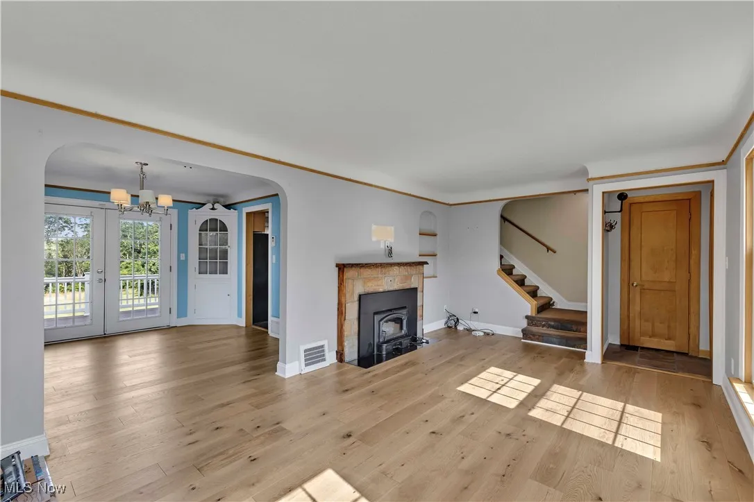 Unfurnished living room with a chandelier, stairs, and light wood-type flooring