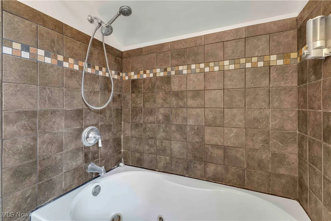 Full bath featuring a combined bath / shower with jetted tub