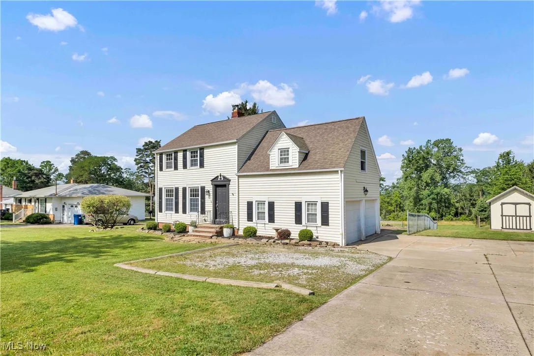 View of front of property featuring driveway, a shed, roof with shingles, a garage, and a front yard