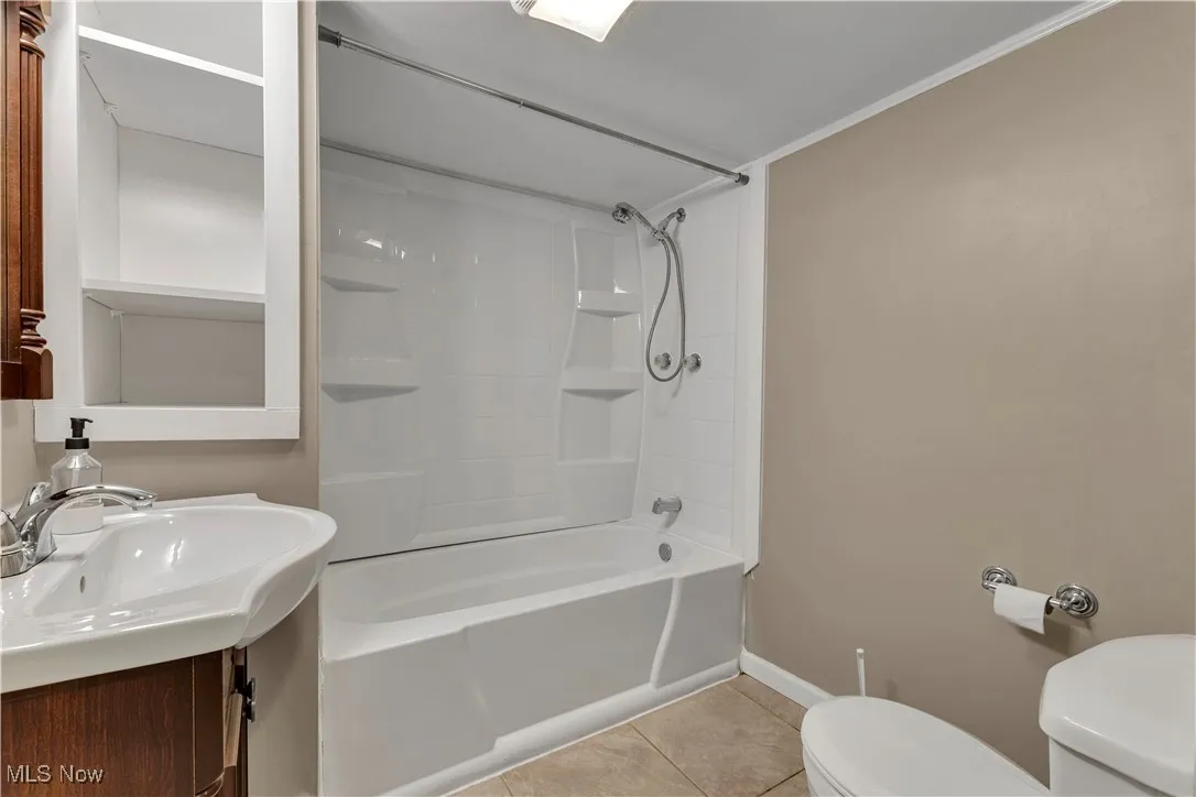 Bathroom with shower / washtub combination, tile patterned flooring, and vanity