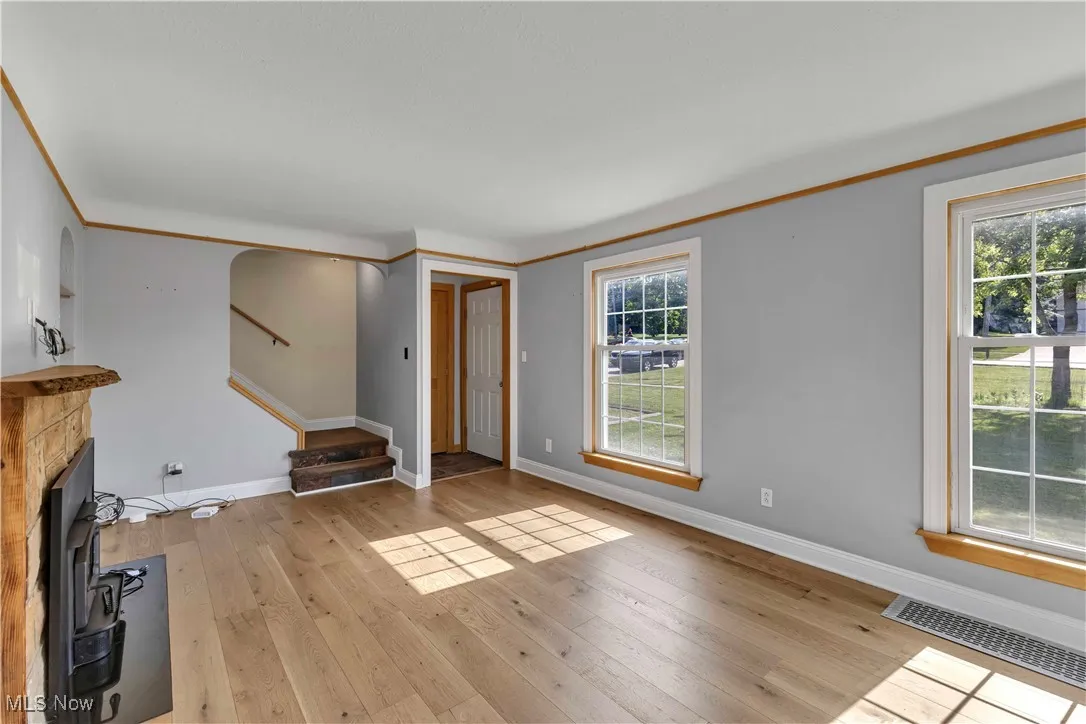 Unfurnished living room featuring stairs and light wood-style flooring