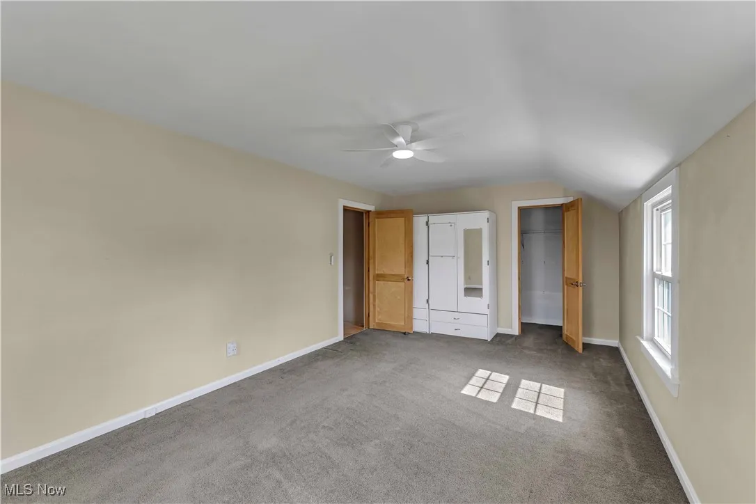 Unfurnished bedroom with carpet, vaulted ceiling, and ceiling fan
