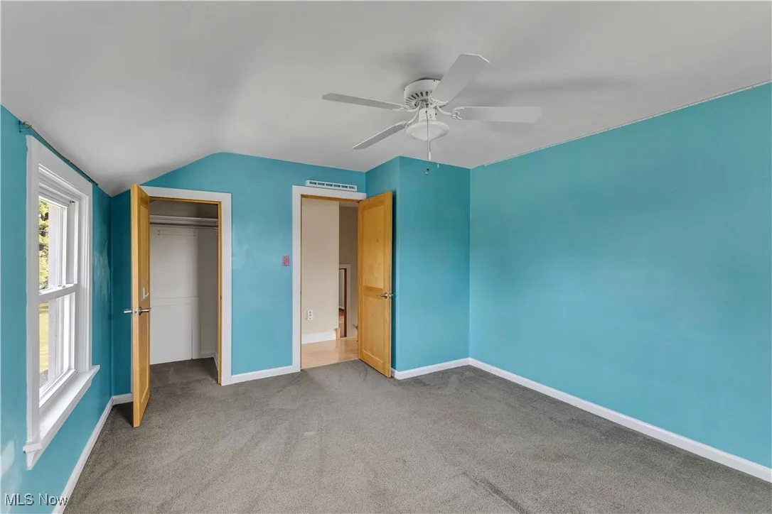 Unfurnished bedroom with carpet flooring, vaulted ceiling, a closet, and ceiling fan