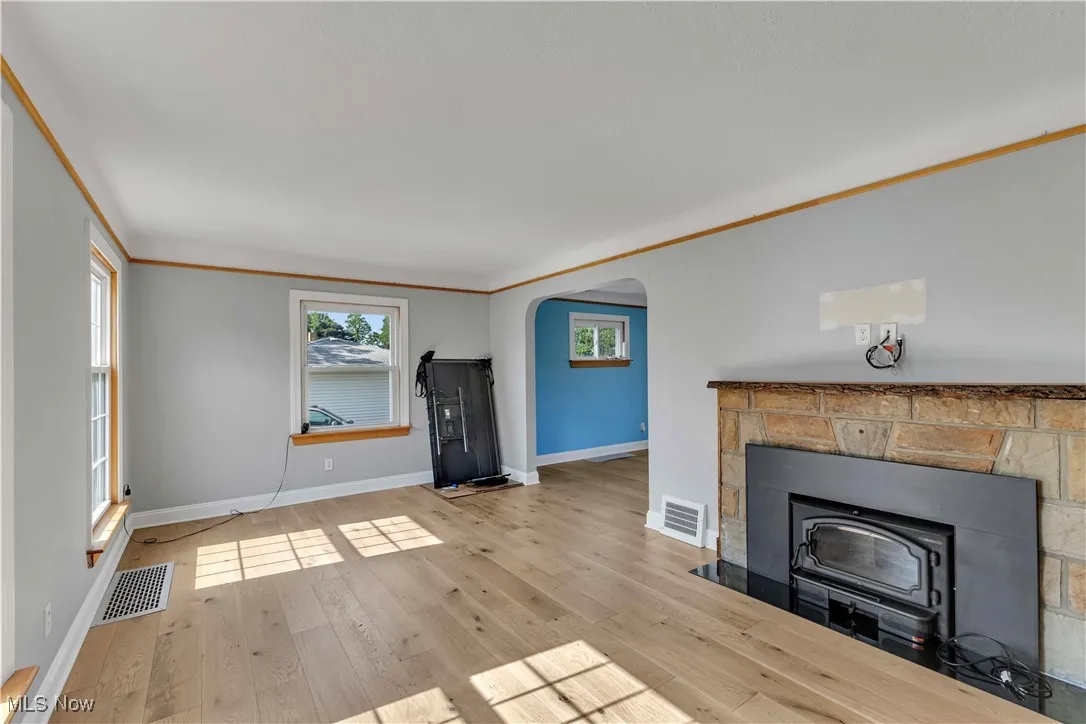 Unfurnished living room with arched walkways and wood finished floors