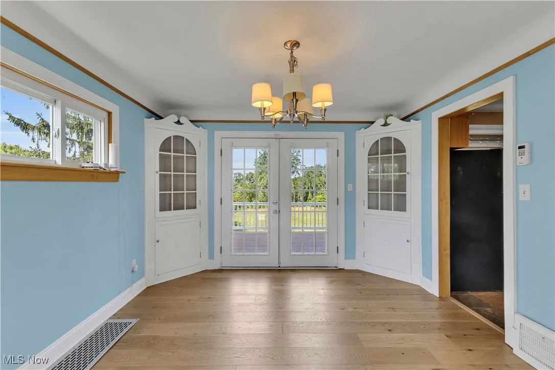 Unfurnished dining area featuring a chandelier, wood finished floors, and french doors