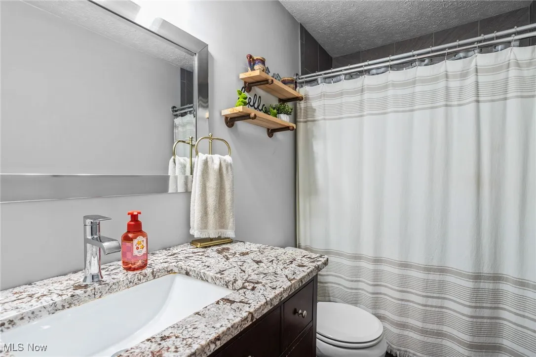 Full bath featuring vanity, a textured ceiling, and a shower with shower curtain
