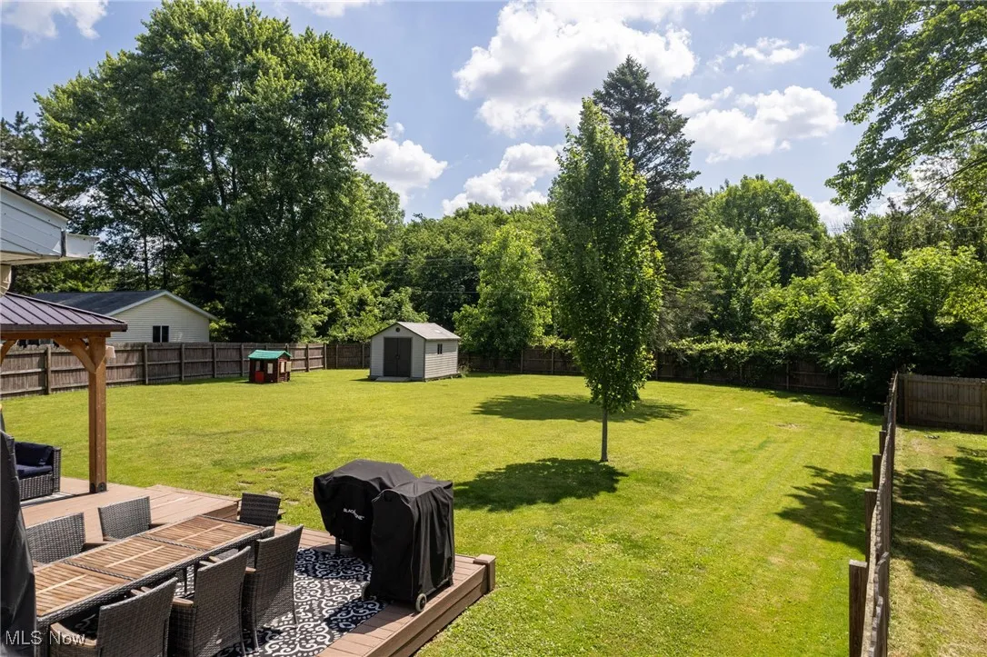 Fenced backyard with a storage shed, outdoor dining space, and a gazebo