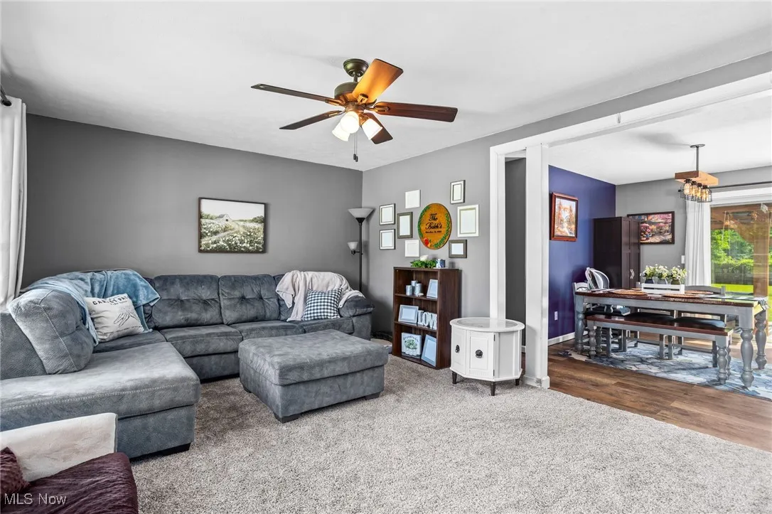 Living area with a ceiling fan, carpet floors, and a chandelier