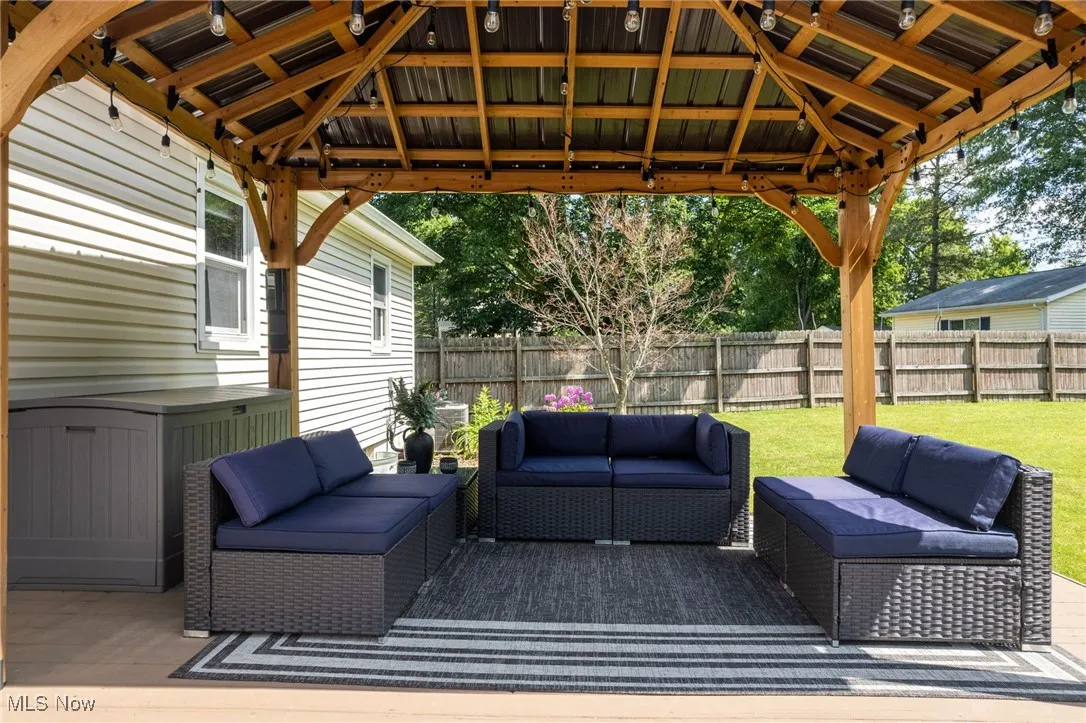 Wooden terrace featuring an outdoor hangout area, a fenced backyard, and a gazebo
