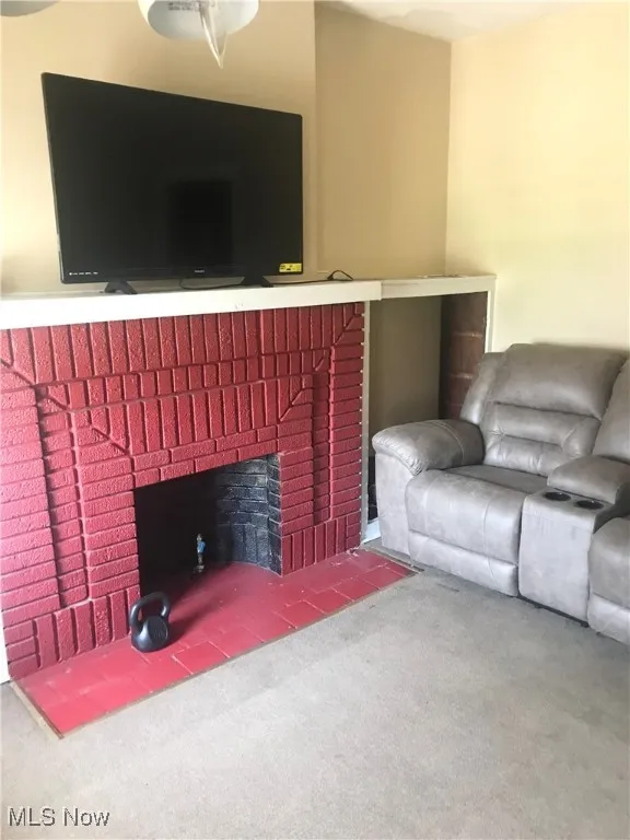 Living room featuring carpet floors, a brick fireplace, and ceiling fan