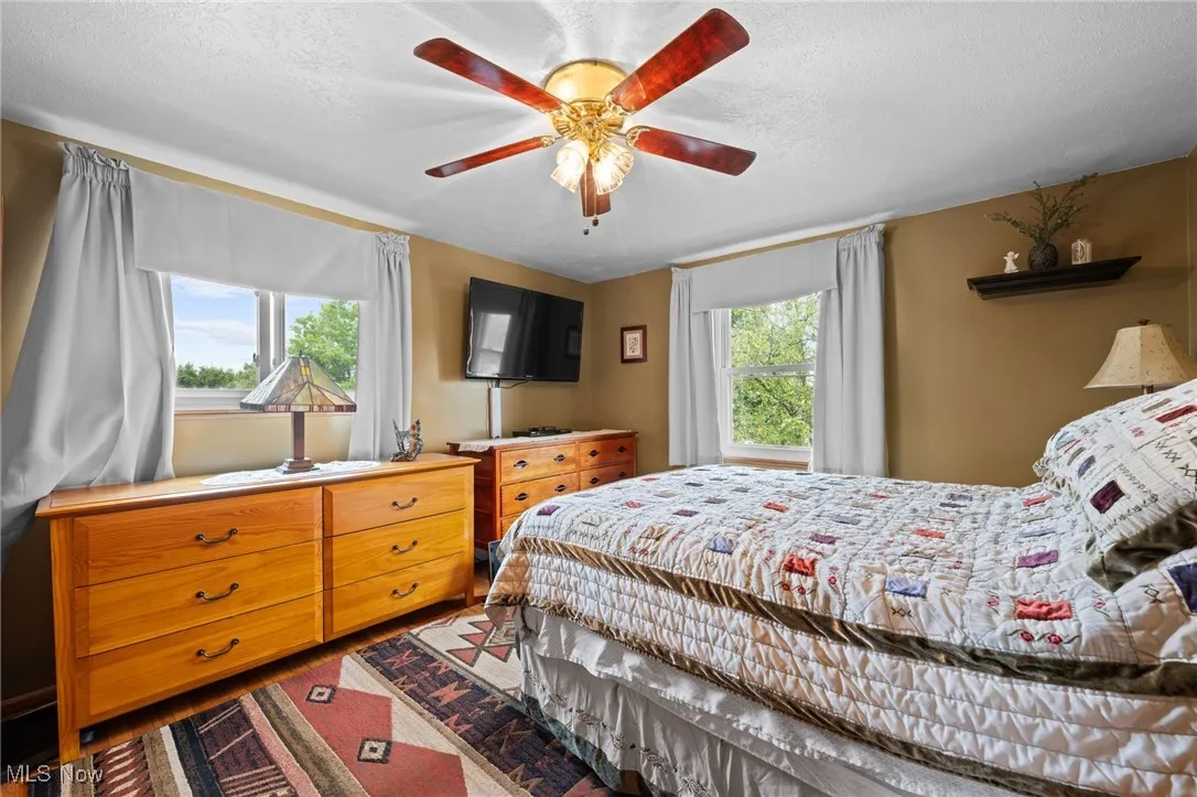 Bedroom with wood finished floors, a ceiling fan, and a textured ceiling